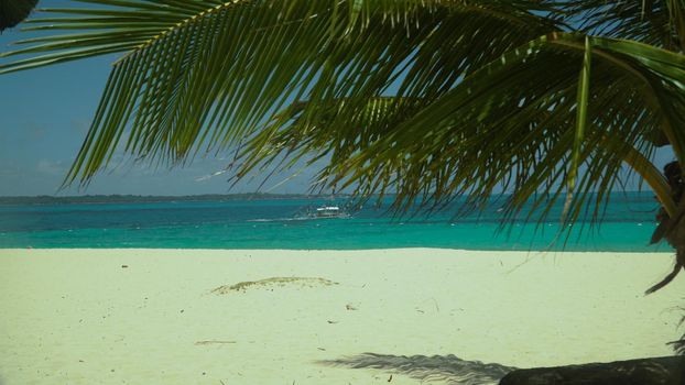 Tropical sandy beach and blue sea through palm branches. Summer and travel vacation concept. Boracay, Philippines
