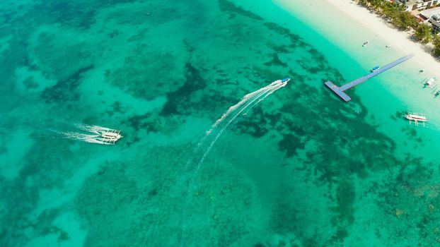 Lagoon with turquoise water and speed boat, top view. Seascape with beach on tropical island. Summer and travel vacation concept. Boracay Island, Philippines