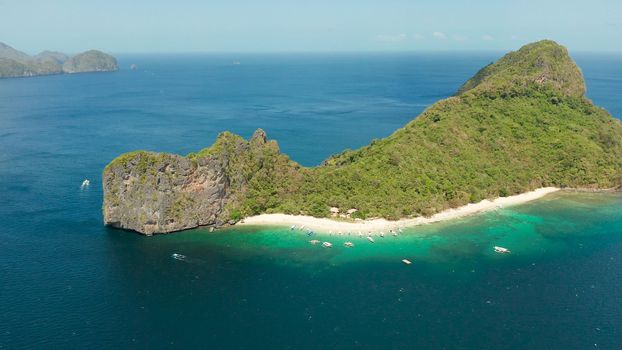 aerial view tropical beach on island with palm trees, blue lagoon and azure clear water. Helicopter Island in El Nido, Palawan Philippines. Tropical landscape with blue lagoon, coral reef