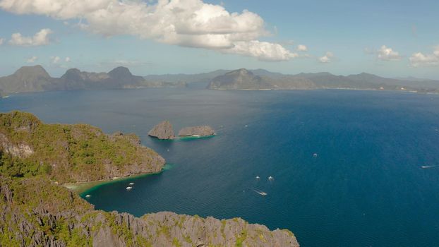 aerial view of bay with tourist boats and the tropical islands. Seascape with tropical rocky islands, ocean blue water. islands and mountains covered with tropical forest. El nido, Philippines, Palawan. Tropical Mountain Range