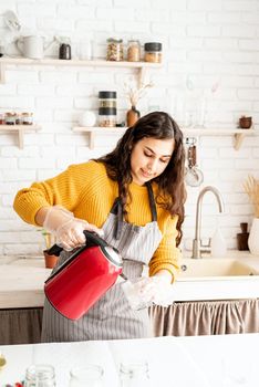 Beautiful brunette woman in yellow sweater and gray apron preparing to color easter eggs in the kitchen