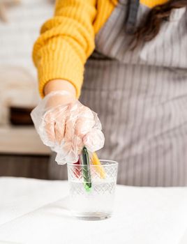 Beautiful brunette woman in yellow sweater and gray apron preparing to color easter eggs in the kitchen