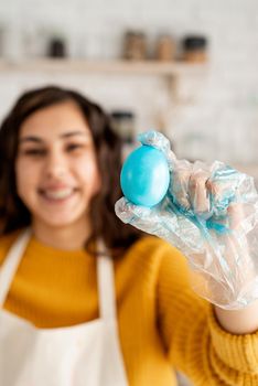 close up of woman hand in glove holding blue easter egg