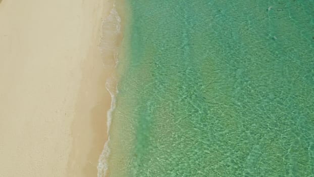 Sea water surface in lagoon with sandy beach and wave, copy space for text, aerial view. Top view transparent turquoise ocean water surface. background texture