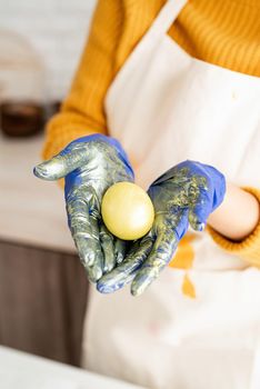 Woman hands holding yellow colored easter egg