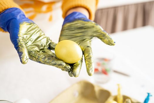 Woman hands holding yellow colored easter egg