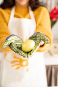 Woman hands holding yellow colored easter egg