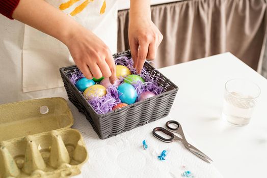 Beautiful smiling brunette woman in red sweater and white apron decorating colorful easter eggs