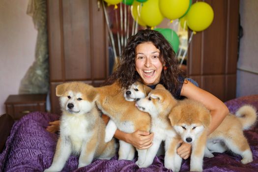 Handsome brunette girl have fun hugs and play with akita inu puppies.