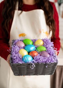 woman hands holding basket with colorful easter eggs