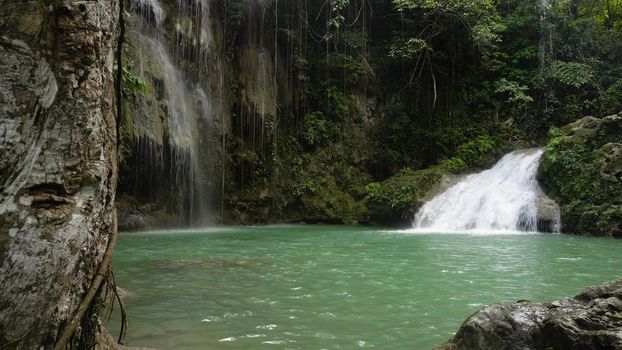 Waterfall in green forest in jungle. Beautiful waterfall in the mountains. Tropical rain forest with waterfall. Philippines, Cebu. Travel concept.