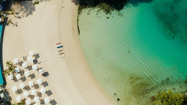 Tropical sandy beach with sun beds near the lagoon with turquoise water from above, Boracay, Philippines, aerial view. Seascape with beach on tropical island. Summer and travel vacation concept.