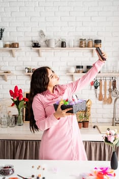 Beautiful brunette woman taking selfie using mobile phone in the kitchen