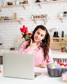 Funny brunette woman in rabbit ears greeting her friends online, celebrating easter