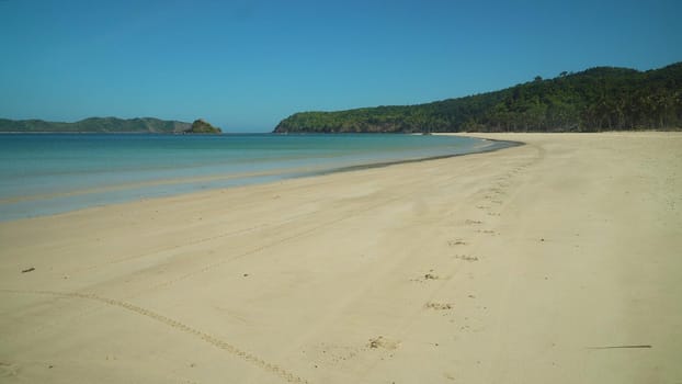 Tropical beach and blue sea with waves. Nacpan, El Nido, Palawan, Philippines. Seascape with sea, sand, palm trees. Summer and travel vacation concept