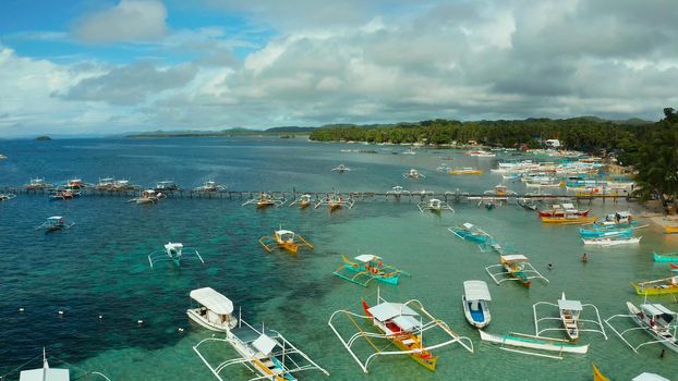 Boats waiting for tourists on a tropical beach in blue water, aerial view. Summer and travel vacation concept.