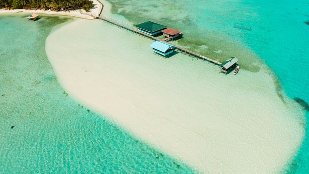 Tropical island among coral reefs with a white beach and blue atoll water. Onok Island, Balabac, Philippines. Summer and travel vacation concept