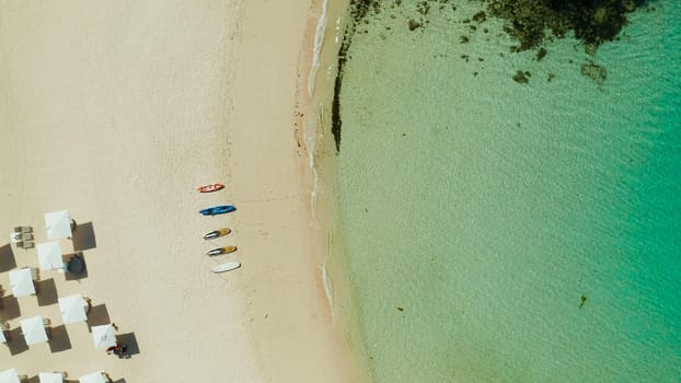 Tropical sandy beach with sun beds near the lagoon with turquoise water from above, Boracay, Philippines, aerial view. Seascape with beach on tropical island. Summer and travel vacation concept.