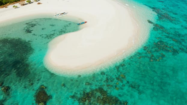 Aerial view of sandy beach on a tropical island with palm trees by coral reef atoll. Patawan island with sandy beach. Summer and travel vacation concept.