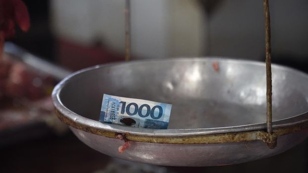 Money on the weighing scales in the street market. 1000 Philippine Pesos on an old scale. Shopping concept.