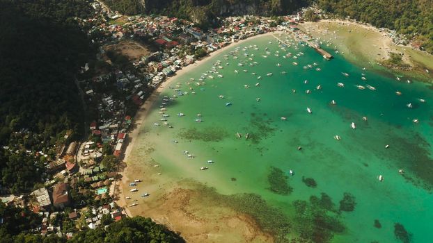 Town El nido on the coast with bay and lot tourist boats, Palawan, Philippines aerial view. Seascape with blue bay and boats view from above. Summer and travel vacation concept