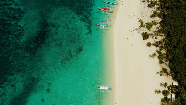 Aerial seascape: Tropical beach with palm trees and turquoise waters of the coral reef, from above, Puka shell beach. Boracay, Philippines. Seascape with beach on tropical island. Summer and travel vacation concept.