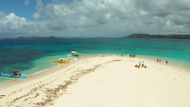Tropical white island and sandy beach with tourists surrounded by coral reef and blue sea, aerial view. Naked Island, Siargao Summer and travel vacation concept