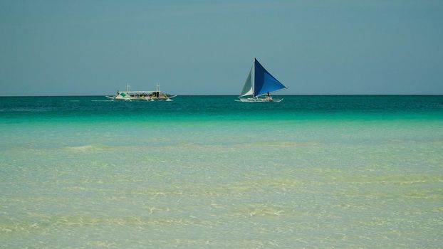 Seascape: tropical beach and sailing yacht in crystal clear turquoise water. Summer and travel vacation concept. Boracay, Philippines