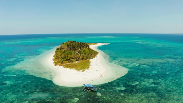 Small tropical island in the blue sea with a coral reef and the beach, top view. Summer and travel vacation concept. Canimeran Island, Balabac, Palawan, Philippines.