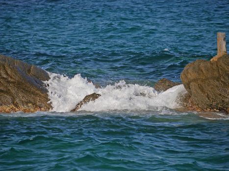 sea wave crashing against the rock cliff