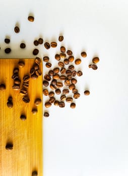 Coffee beans lie on wooden board and white table