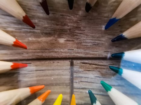 Colorful pencil crayons lie in a circle on wooden floor