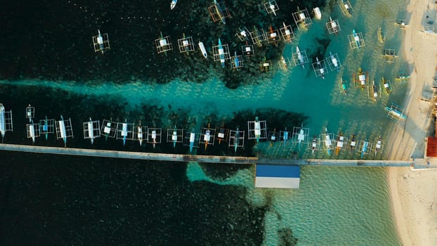 Long pier with moored boats in the morning, aerial view. General Luna, Siargao island.
