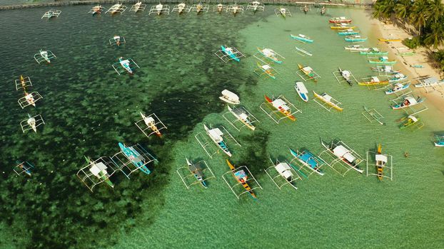 Boats waiting for tourists on a tropical beach in blue water, aerial view. Summer and travel vacation concept.