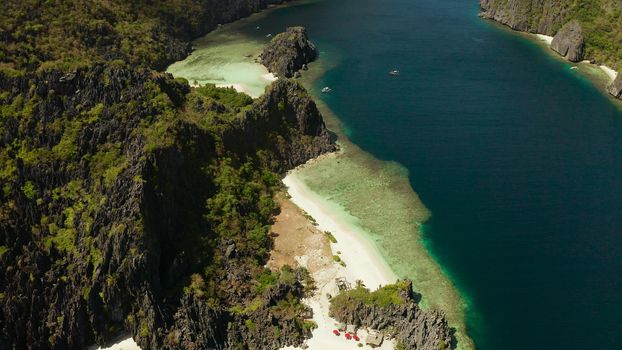 Tropical landscape bay with beach and clear blue water surrounded by cliffs, aerial drone. El nido, Philippines, Palawan. Seascape with tropical rocky islands, ocean blue water. Summer and travel vacation concept
