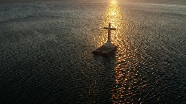 Catholic cross in sunken cemetery in the sea at sunset, aerial view. Sunset at Sunken Cemetery Camiguin Island Philippines.