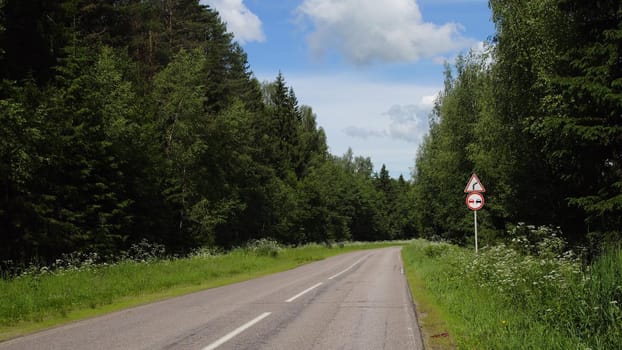 Road sign warning of dangerous right curve and sign no passing on the highway in the forest.