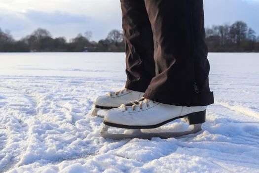 Close up on womans feet wearing ice skating boots and standing on ice