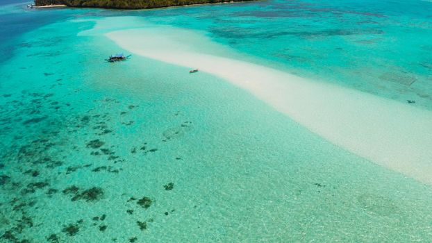 Sandy beach with tourists among turquoise waters and coral reefs. Mansalangan sandbar. Beach at the atoll. Summer and travel vacation concept. Balabac, Palawan, Philippines.