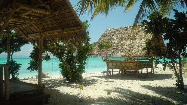 Bungalow on a tropical beach with palm trees and blue sea of Daco, Philippines. Summer and travel vacation concept