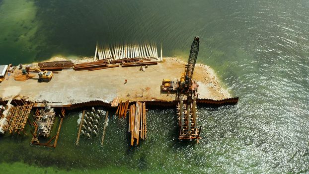 The bridge under construction across the bay and construction equipment with workers on the bridge. Siargao, Philippines.