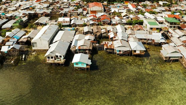 Fishing village with boats and slums with wooden houses, aerial drone. Dapa, Siargao, Philippines.