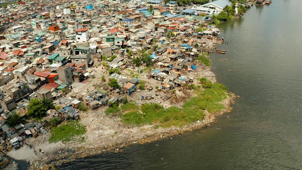 Slums near the port in Manila on the bank of a river polluted with garbage, aerial view.