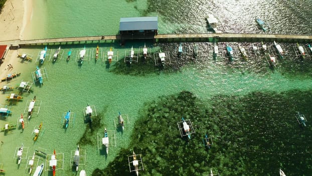 Long pier with moored boats on the beach, aerial view. General Luna, Siargao island.