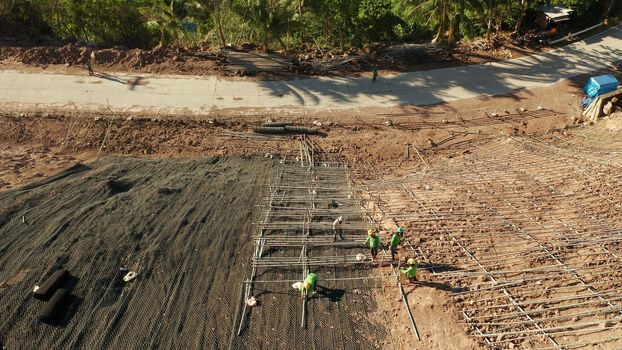 Protection of road from mountain slough, rockfall with metal accumulative restraining net fences. Workers constructing anti-landslide concrete wall prevent protect against rock slides. Rockfall protection. Workers strengthen the slope of the mountain with steel grid preventing rockfall and landslide on the road.