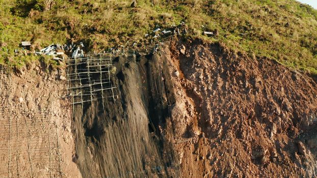 Protection of road from mountain slough, rockfall with metal accumulative restraining net fences. Workers constructing anti-landslide concrete wall prevent protect against rock slides. Rockfall protection. Workers strengthen the slope of the mountain with steel grid preventing rockfall and landslide on the road.