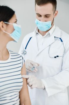 male doctor in a white coat make an injection in the hand of a woman patient health. High quality photo