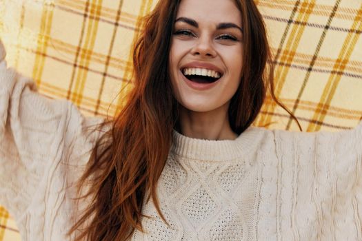 a woman with a checkered plaid over her head and in a warm sweater beautiful smile. High quality photo