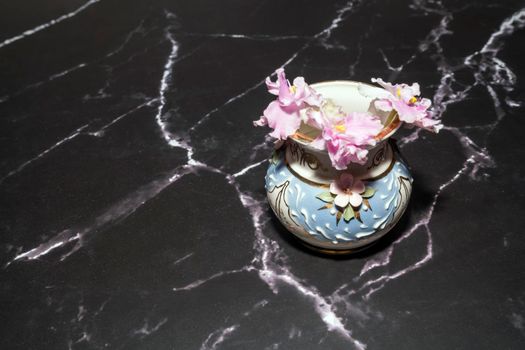 pink violets in a vase on the marble floor. High quality photo