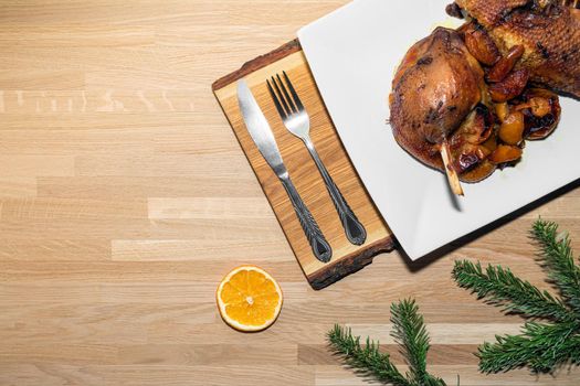 roast goose with apples on a wooden background. christmas dish with spruce twigs and orange. the view from the top. High quality photo